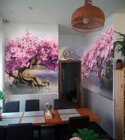 Interiér asijského bistra v Praze s velkou malbou na zdi zobrazující rozkvetlý sakura strom a horskou krajinu