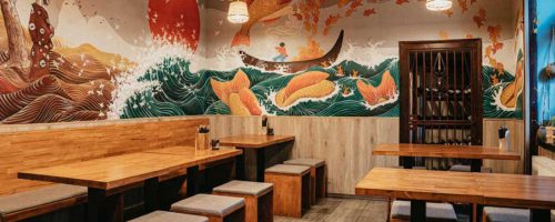 Umělecká malba na zdi restaurace v Praze, zobrazující dynamickou scénu s vlnami a koiovými kapry ve stylu tradičního japonského umění
