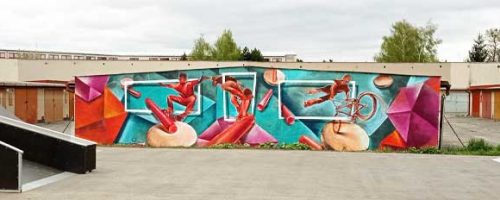 Mural art ve graffiti stylu v skate parku v Kroměříži, zobrazující dynamické scény s figurami provádějícími triky na skateboardu a kole, obklopené živými geometrickými tvary a intenzivními barvami, což oživuje prostor pro mladé sportovce.